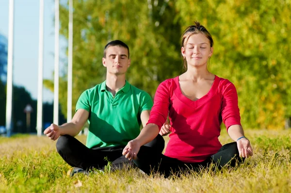 Homme et femme faisant du yoga dans le parc — Photo