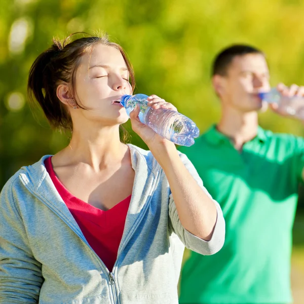 Man and woman drinking from bottle — Stock Photo, Image