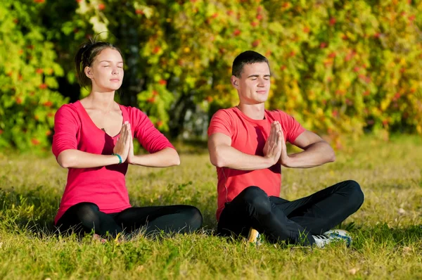 Man och kvinna kvinna gör yoga i park — Stockfoto