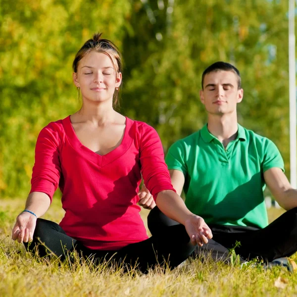 Homme et femme faisant du yoga dans le parc — Photo