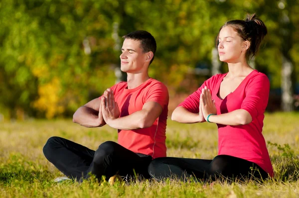 Man och kvinna kvinna gör yoga i park — Stockfoto