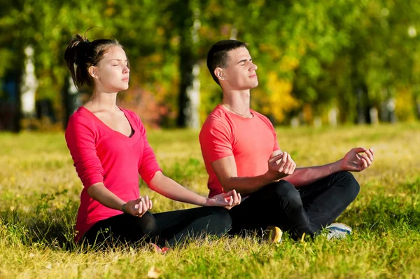 Homme et femme faisant du yoga dans le parc — Photo