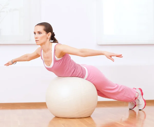 Kvinna göra stretching motion på boll — Stockfoto