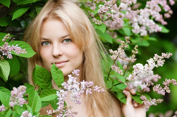 顔にライラックの花を持つ女性 ロイヤリティフリーのストック写真