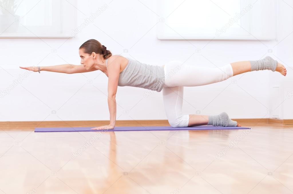 Woman doing stretching yoga exercise at sport gym