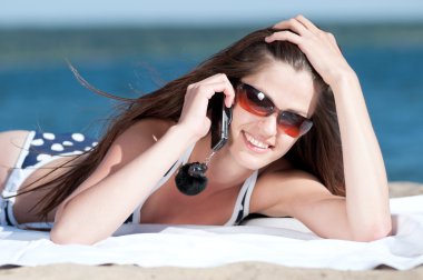 bir sahilde telefonla konuşan kadın