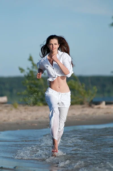 Mulher desportiva correndo na costa do mar — Fotografia de Stock