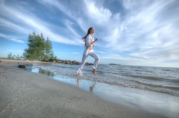 Mujer deportiva corriendo en la costa del mar — Foto de Stock