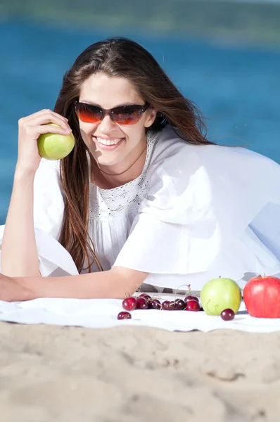 Vrouw op strand eten vruchten — Stockfoto