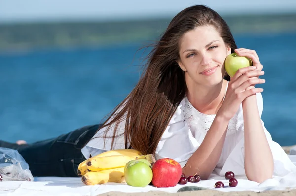 Γυναίκα στην παραλία τρώει φρούτα — Φωτογραφία Αρχείου