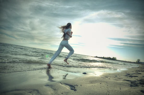 Sportliche Frau läuft in Meeresküste — Stockfoto