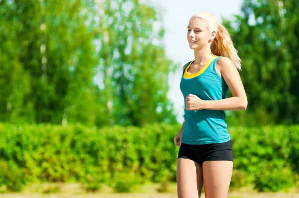 Молода жінка біжить у зеленому парку — стокове фото