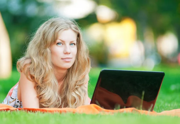 Giovane donna con computer portatile al parco — Foto Stock