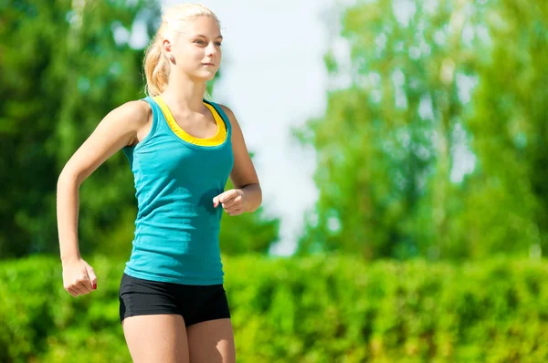 Jeune femme courant dans un parc vert Image En Vente