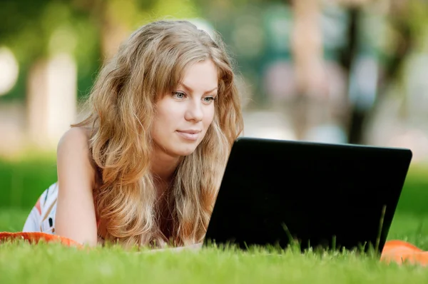 Ung kvinna med laptop på park — Stockfoto