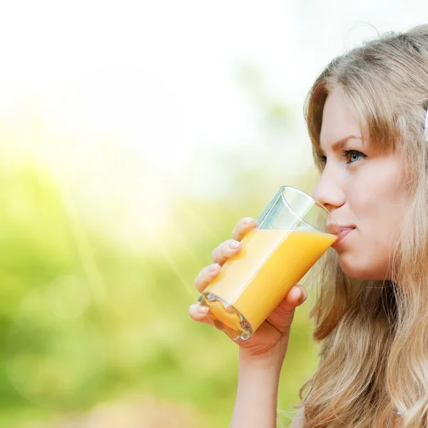 Lächelnde Frau trinkt Orangensaft — Stockfoto