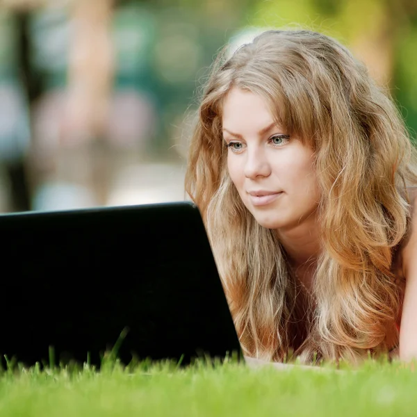 Ung kvinna med laptop på park — Stockfoto