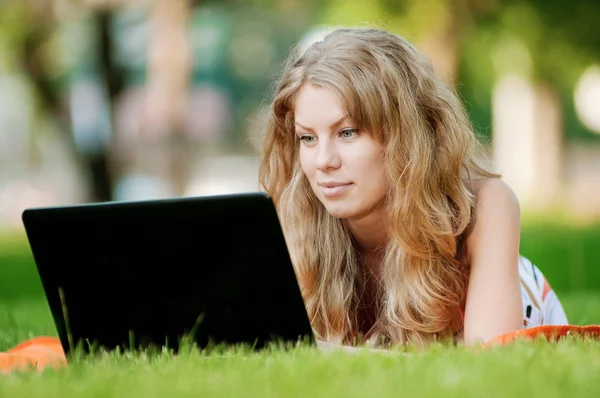 Giovane donna con computer portatile al parco — Foto Stock