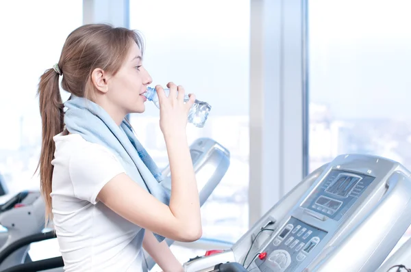 Una donna in palestra che si allena. Corri su una macchina e bevi acqua — Foto Stock