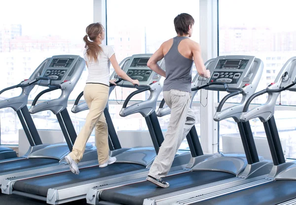 Mujer joven y hombre en el gimnasio haciendo ejercicio. Correr. — Foto de Stock