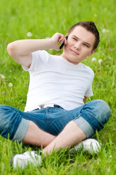 Um jovem com telefone no parque verde da cidade — Fotografia de Stock