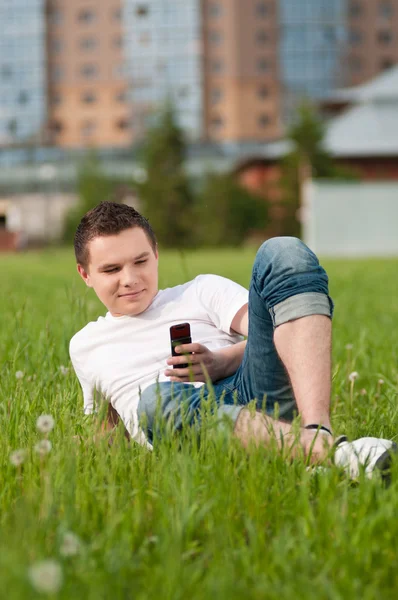 Een jonge man met telefoon op groene stadspark — Stockfoto