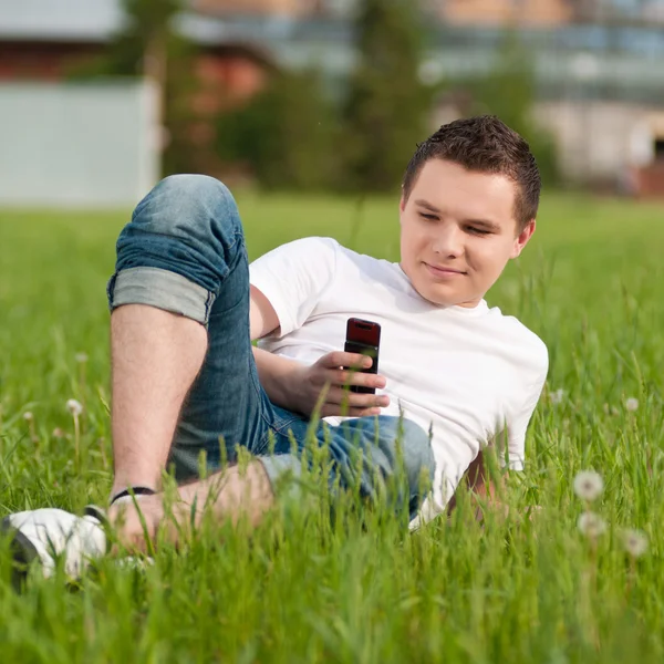 Een jonge man met telefoon op groene stadspark — Stockfoto