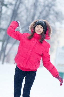 Mutlu genç kadın karla oynuyor.