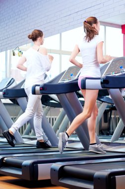 makine üzerinde çalışan iki genç sportif kadın