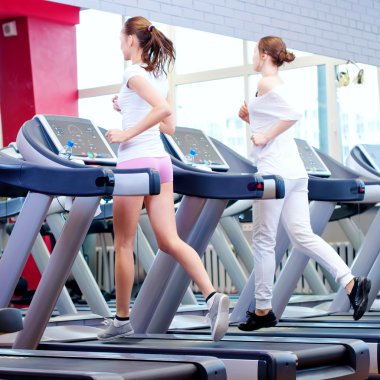 makine üzerinde çalışan iki genç sportif kadın