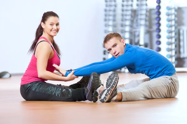 Hombre y mujer en el gimnasio haciendo estiramiento —  Fotos de Stock