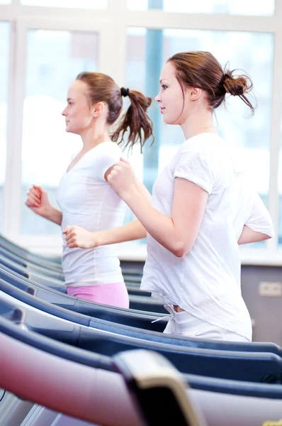 Two young sporty women run on machine — Stock Photo, Image