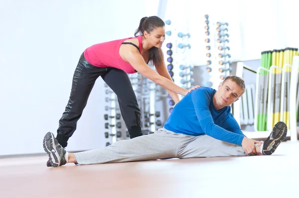 Man and woman at the gym doing stretching — Stock Photo, Image