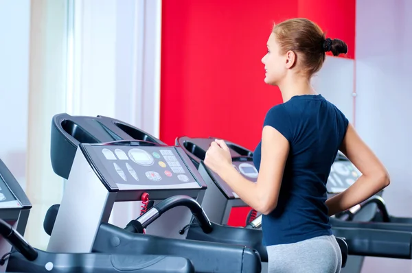 Mujer joven en el gimnasio se ejecuta en una máquina — Foto de Stock