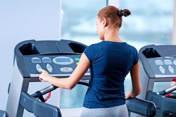 Jeune femme à la salle de gym courir sur une machine — Photo