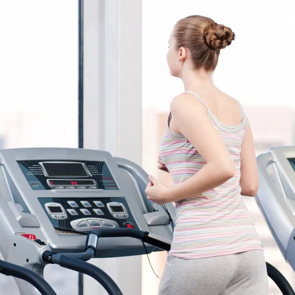 Mujer en el gimnasio haciendo ejercicio. Ejecutar en máquina —  Fotos de Stock