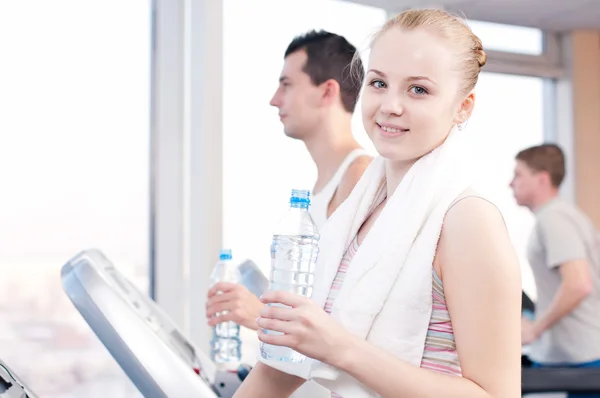 Homme et femme boivent de l'eau après le sport en salle de gym — Photo