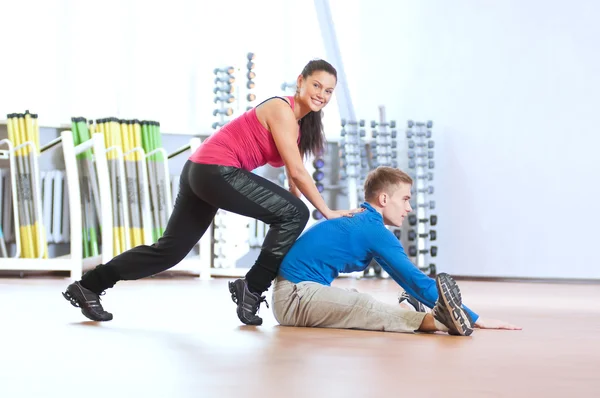 Мужчина и женщина в спортзале делают растяжку — стоковое фото