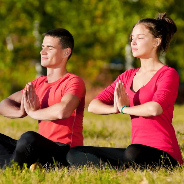 Homme et femme faisant du yoga dans le parc — Photo