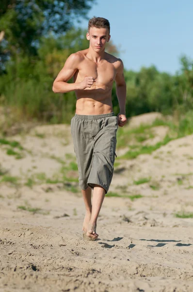 Young man running on beach — Stock Photo, Image