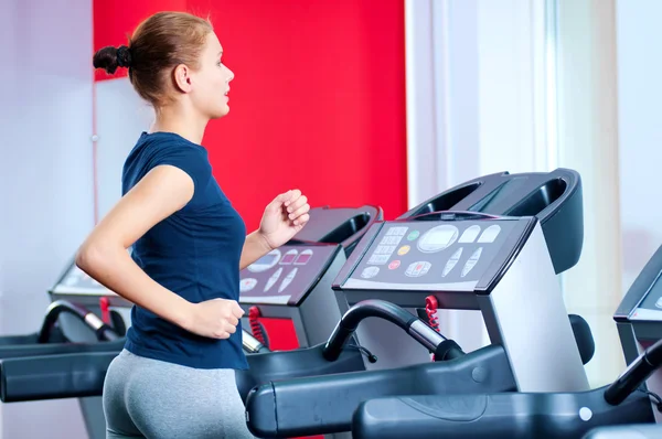 Mujer joven en el gimnasio se ejecuta en una máquina — Foto de Stock