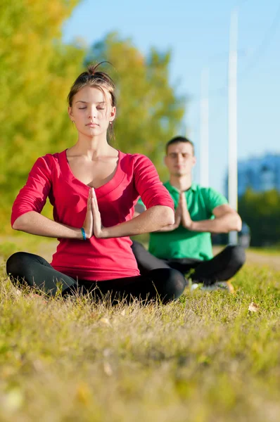 Man and woman woman doing yoga in park — Stock Photo, Image