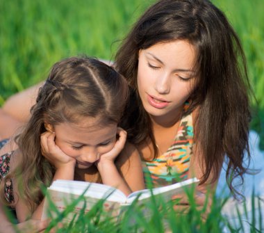 mutlu kız yeşil çimenlerin üzerinde kitap okuma