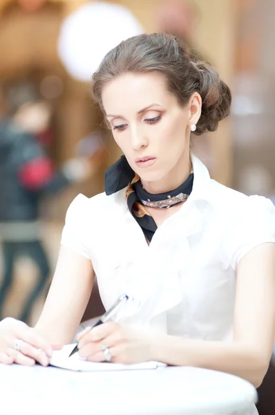 Affärskvinna skriver med pennan i organizer — Stockfoto