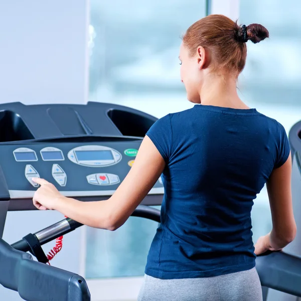 Jeune femme à la salle de gym courir sur une machine — Photo