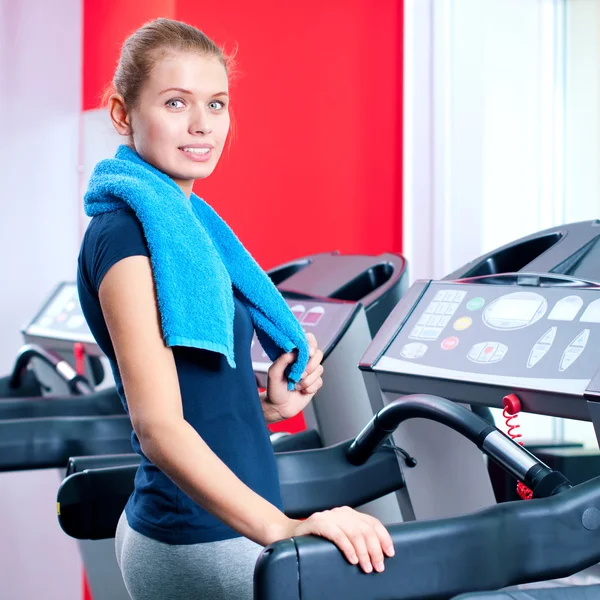 Νεαρή γυναίκα στο γυμναστήριο τρέχω επάνω σε μια μηχανή — Φωτογραφία Αρχείου