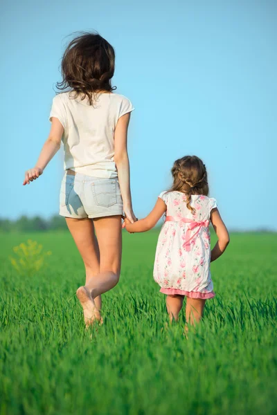 Giovani ragazze felici che corrono al campo di grano verde — Foto Stock