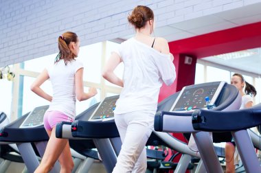 makine üzerinde çalışan iki genç sportif kadın