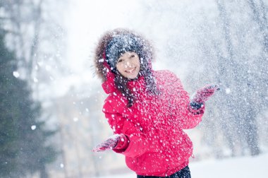 Mutlu genç kadın karla oynuyor.