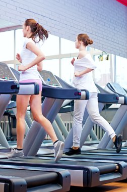 makine üzerinde çalışan iki genç sportif kadın